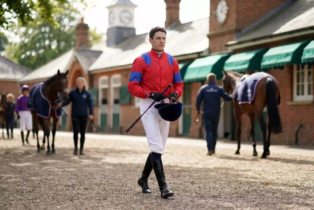 Jockey in colourful racing silks walking through weighing room